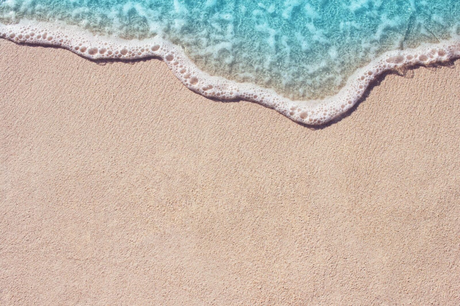 Soft wave of blue ocean on sandy beach. Background.